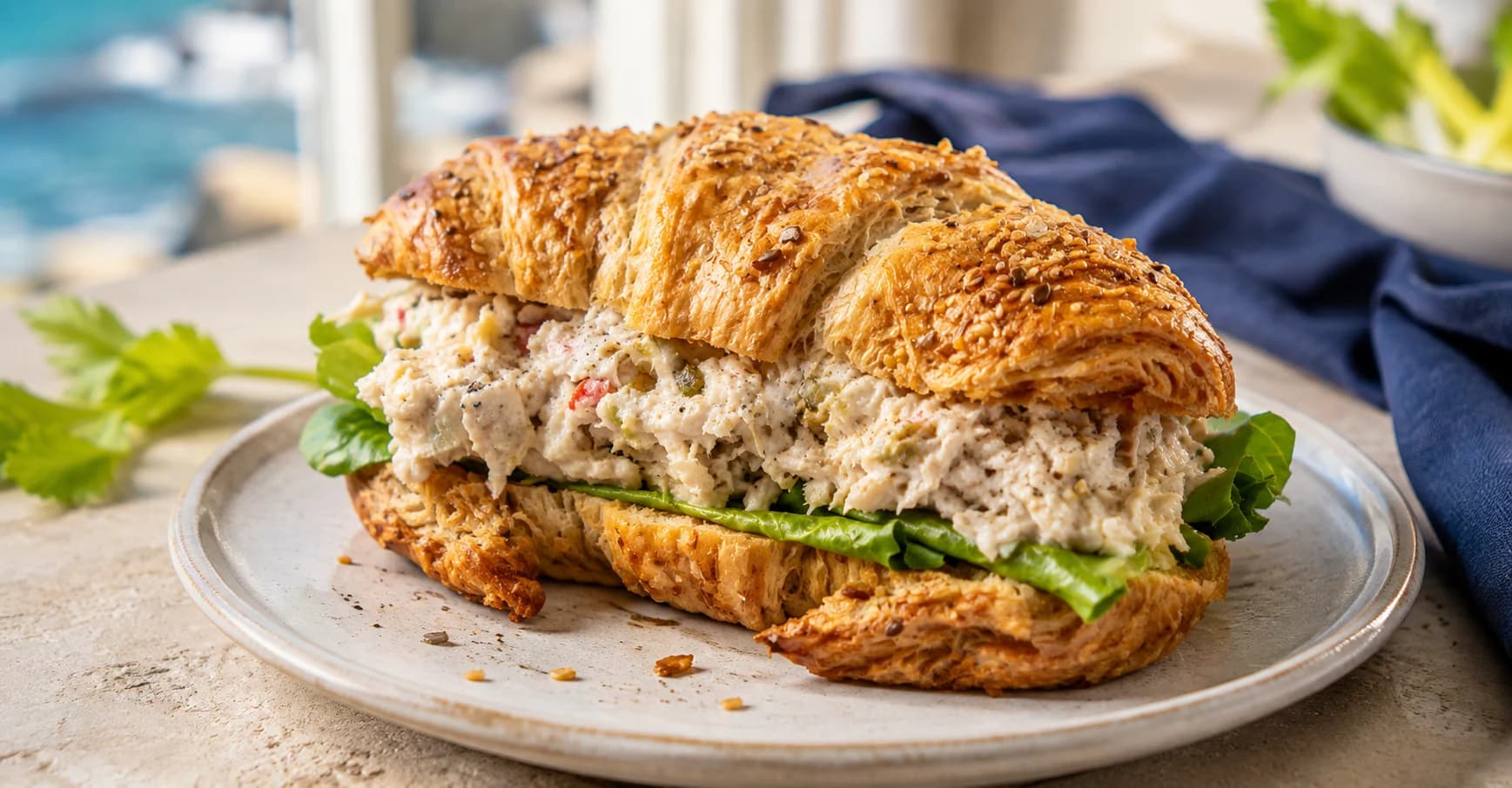 A flaky croissant generously filled with chicken salad and greens